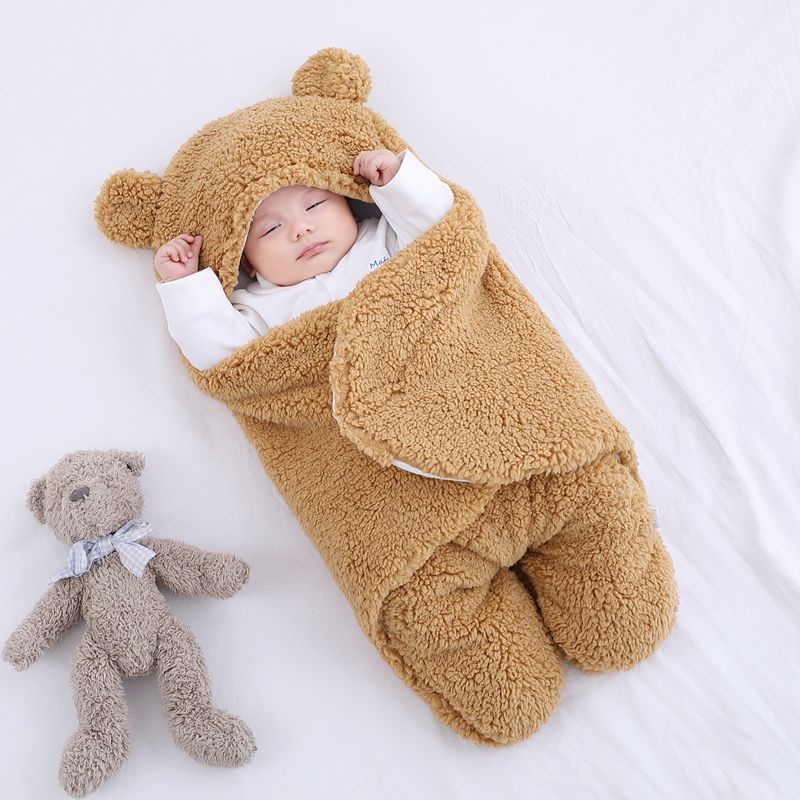 Baby i beige sovpåse med björnöron